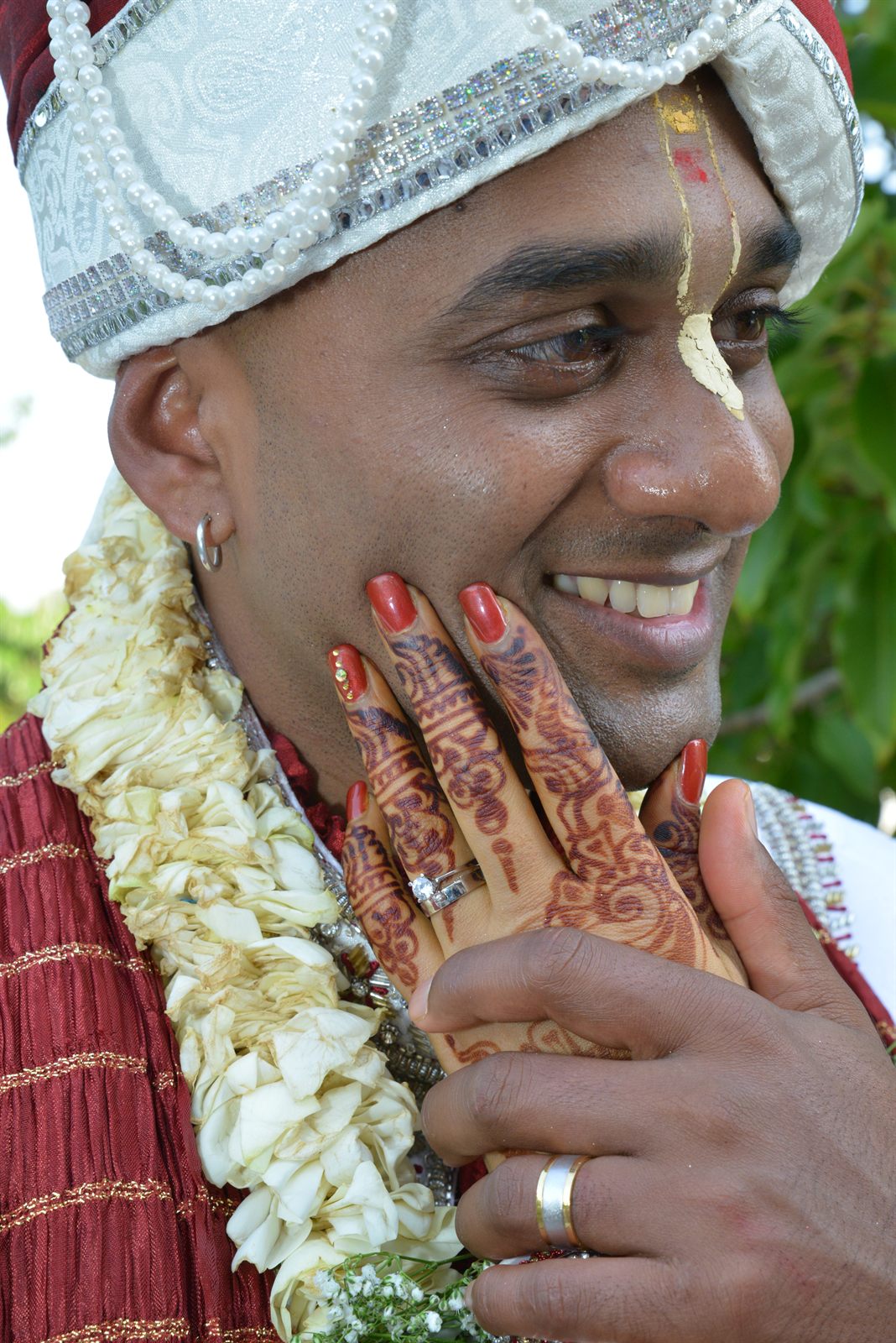 Henna-painted hands held to a smiling face